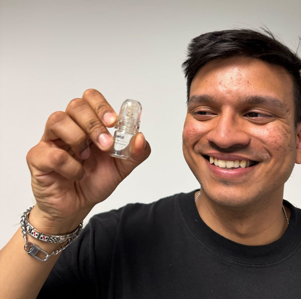 A man smiling while holding a Petal Microneedling Infusion System in his hand