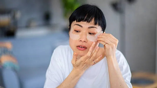 Woman placing hydrating eye patches under eyes
